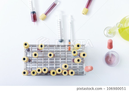 Top view of blood samples in tubes and syringes on work table in a medical examination lab. Top view of blood samples in tubes and syringes on work table in a medical examination lab. 106980051