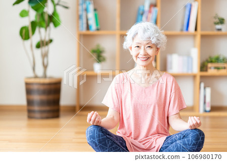 一位老年婦女在客廳裡做瑜伽。 一位老年婦女在客廳裡做瑜伽。 106980170
