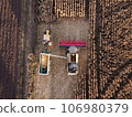 Top view of a combine that loads corn grain on a tractor trailer for further transportation to the farm 106980379