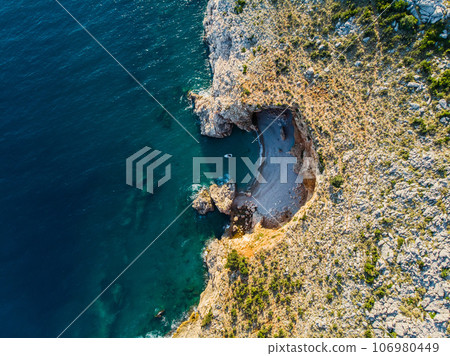 Top view of a beautiful sea harbor. Lagoon with dark blue water. Waves near rocky coast and boat Top view of a beautiful sea harbor. Lagoon with dark blue water. Waves near rocky coast and boat 106980449