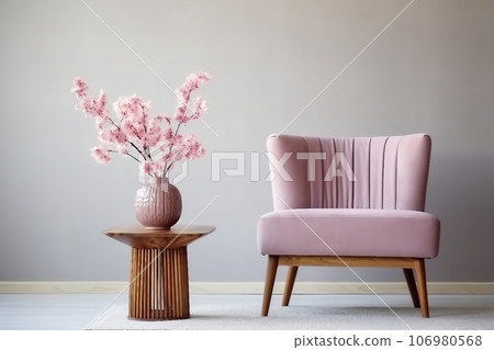 Cute pink flowers in glass vase placed on wooden table standing by small chair 106980568
