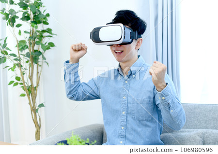 A young man in casual clothes wearing VR goggles A young man in casual clothes wearing VR goggles 106980596