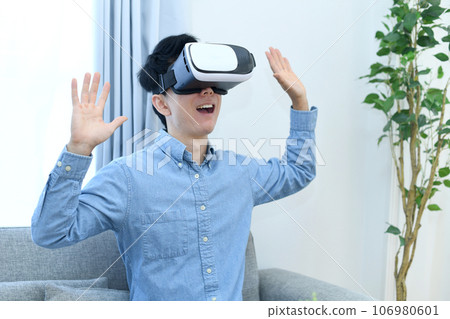A young man in casual clothes wearing VR goggles 106980601