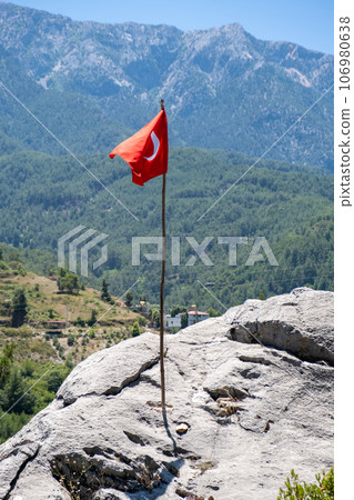 The Turkish flag is flying against the backdrop of beautiful mountains. The waving Turkish flag. The flag of Turkey on a flagpole with a copy space. 106980638