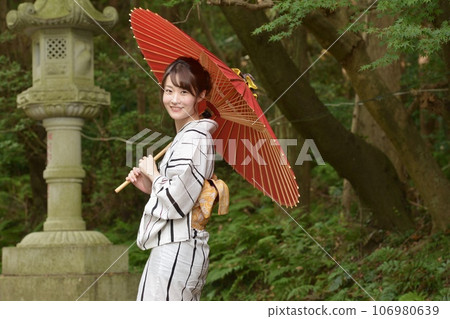 一位身穿浴衣、手裡拿著日本傘的年輕女子 106980639