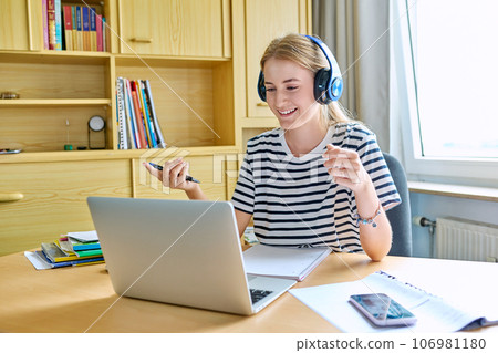 Teenage girl high school student in headphones having video conference on laptop 106981180