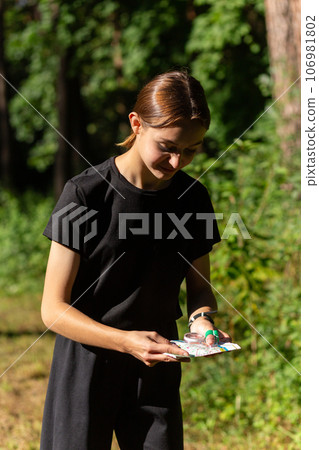 Young girl in forest reading map and searching for a control point. Sports orienteering competition. Young girl in forest reading map and searching for a control point. Sports orienteering competition. 106981802