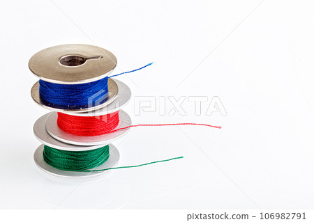 spools of thread in blue, red, green colors on a white background 106982791
