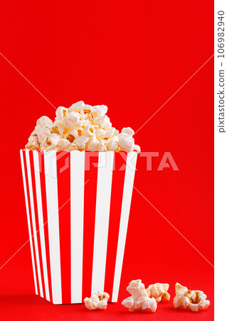 Glass with popcorn on a red background 106982940