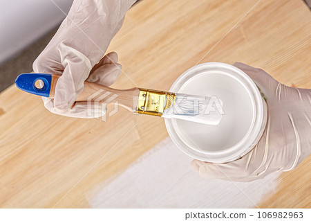 white paint with a brush painting a wooden background with texture 106982963