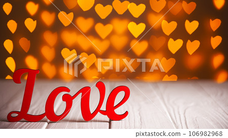 the inscription Love on a wooden background with beautiful hearts made of lights on a blurred background the inscription Love on a wooden background with beautiful hearts made of lights on a blurred background 106982968