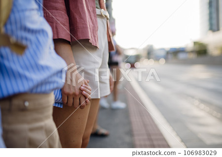 Mother and school girl with a backpack holding hands while crossing a busy road. Mother and school girl with a backpack holding hands while crossing a busy road. 106983029
