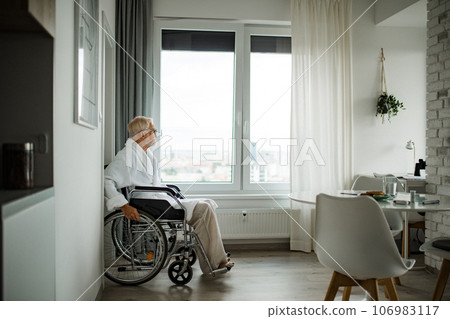 Senior man in a wheelchair spends time alone in his apartment. 106983117