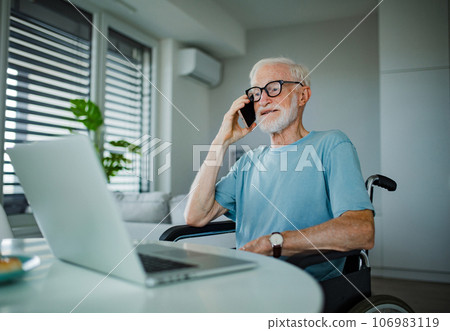 Senior man in a wheelchair working during retirement. 106983119