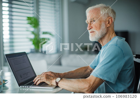 Senior man in a wheelchair working during retirement. 106983120