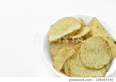 Yellow pieces of fried potatoes in a plate. Salted chips on a white background. Yellow pieces of fried potatoes in a plate. Salted chips on a white background. 106983140