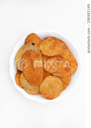 Red pieces of fried potatoes in a plate. Peppery chips on a white background. Red pieces of fried potatoes in a plate. Peppery chips on a white background. 106983149