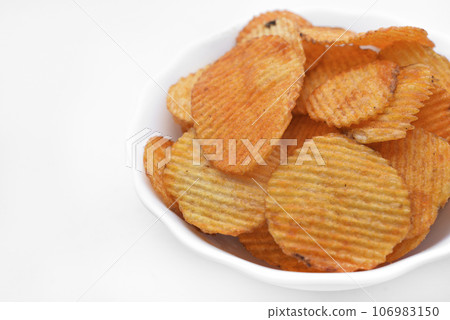 Red pieces of fried potatoes in a plate. Peppery chips on a white background. 106983150