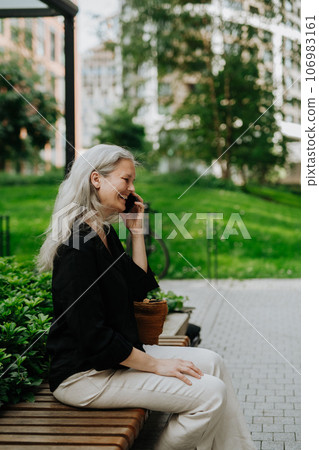 Portrait of a beautiful woman with gray hair making a call outdoors. Portrait of a beautiful woman with gray hair making a call outdoors. 106983161