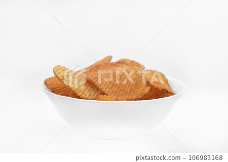 Red pieces of fried potatoes in a plate. Peppery chips on a white background. 106983168