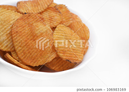 Red pieces of fried potatoes in a plate. Peppery chips on a white background. Red pieces of fried potatoes in a plate. Peppery chips on a white background. 106983169