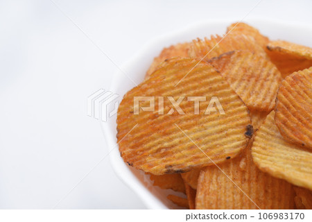 Red pieces of fried potatoes in a plate. Peppery chips on a white background. Red pieces of fried potatoes in a plate. Peppery chips on a white background. 106983170