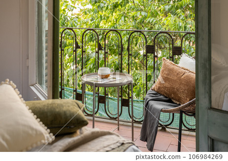 Horizontal shot from hotel room to an open loggia with straw chair on the backdrop of a summer garden in the courtyard. The concept of traveling and staying at a hotel for newlyweds or a young family 106984269