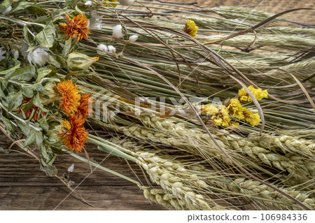 floral autumn bouquet with dried flowers and grain stalks on rustic wood 106984336