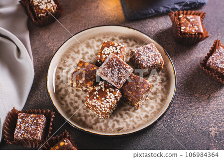Sugar free candies made from fruit paste, nuts and sesame seeds on a plate Sugar free candies made from fruit paste, nuts and sesame seeds on a plate 106984364