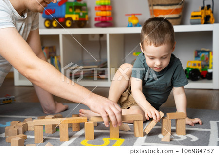 Little toddler boy playing wooden blocks with dad. Spending time with children. Educational activities for kids. Children's room. Indoors 106984737