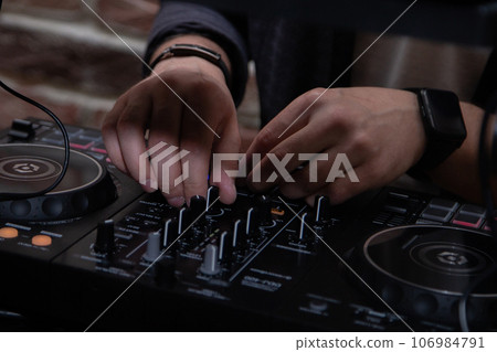 A DJ in a nightclub at the control panel adjusts the music. Music is playing, creating an atmosphere. High quality photo A DJ in a nightclub at the control panel adjusts the music. Music is playing, creating an atmosphere. High quality photo 106984791