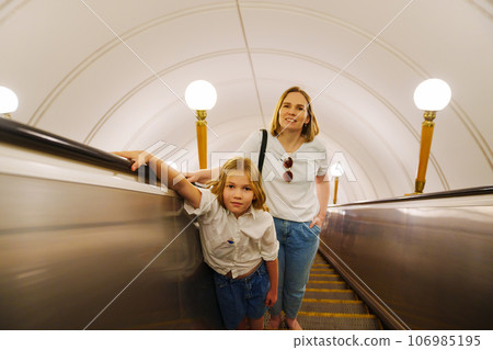 Mom and daughter ride up the escalator in the subway. Mom and daughter ride up the escalator in the subway. 106985195
