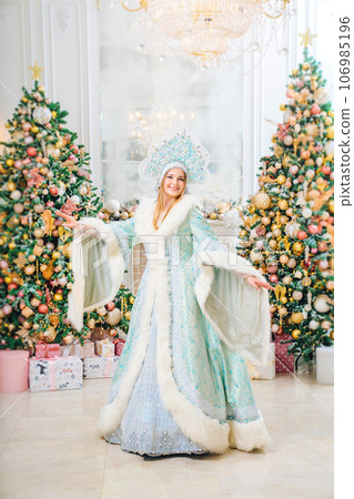 Snow Maiden in a costume with a kokoshnik in a room with christmas tree Snow Maiden in a costume with a kokoshnik in a room with christmas tree 106985196