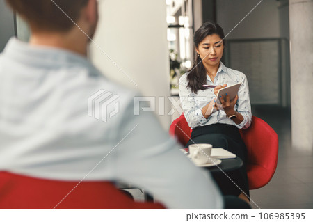 Female HR manager looking on digital tablet during interview with job candidate in office Female HR manager looking on digital tablet during interview with job candidate in office 106985395