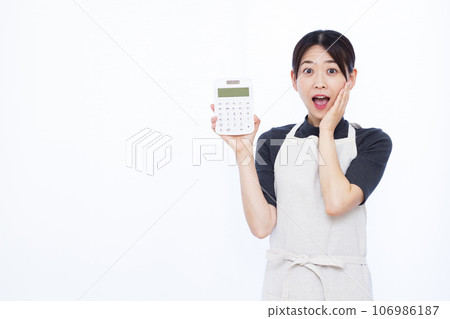 一位 30 多歲的家庭主婦拿著計算器，在白色背景前微笑，感到驚訝 106986187