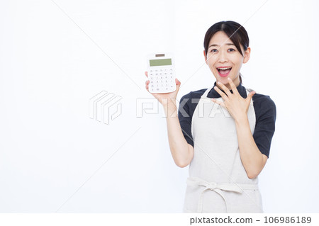 一位 30 多歲的家庭主婦拿著計算器，在白色背景前微笑，感到驚訝 106986189