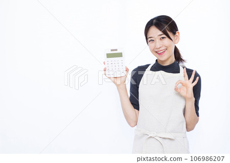 一位 30 多歲的家庭主婦拿著計算器，在白色背景前打出 OK 手勢 106986207