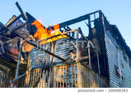 Destroyed by fire raging flames consume home, reducing it to ashes 106986363