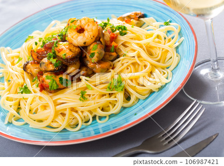 Tasty warm pasta with shrimp and mussels, served with greens Tasty warm pasta with shrimp and mussels, served with greens 106987421