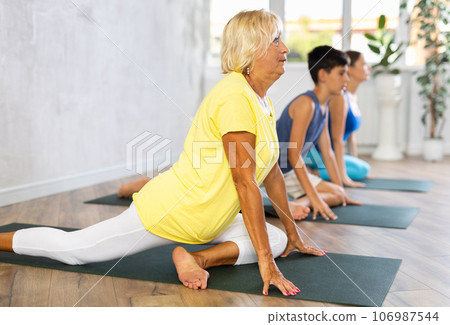 Mother, grandmother and teen son do exercise dove pose, Eka Pada Rajakapotasana. 106987544