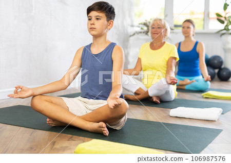 Family three generations do half lotus position Sidhasana with hands clasped in mudra of knowledge 106987576