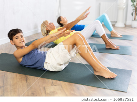 Mom, grandmother and teen grandson performing exercises to strengthen press, pump muscles of core 106987581