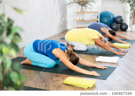 Grandmother, mother and teen son do sitting upside down tree pose, Adho Mukha Virasana in gym Grandmother, mother and teen son do sitting upside down tree pose, Adho Mukha Virasana in gym 106987589
