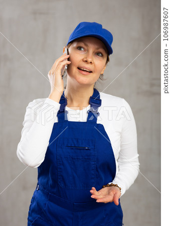 Cheerful female worker with wide grin on her face talking on phone 106987607