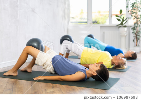 Positive preteen boy practicing lying fitness pose with softball between legs 106987698