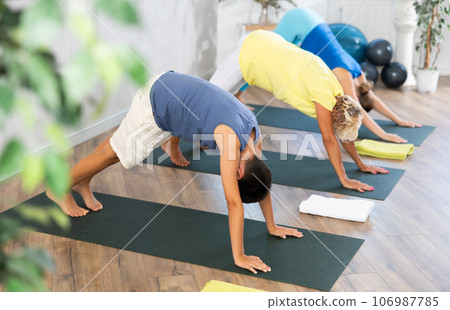 Preteen boy practicing downward facing dog pose of yoga in fitness room 106987785