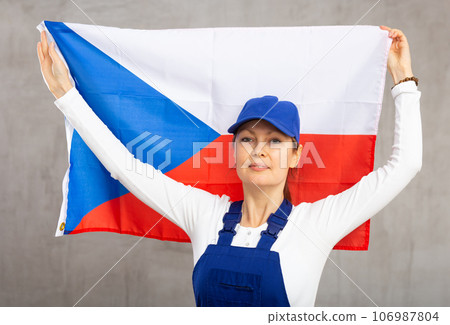 Cheerful female worker with wide grin on her face holding flag of czech republic Cheerful female worker with wide grin on her face holding flag of czech republic 106987804