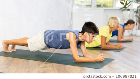 Preteen boy practicing plank pose of yoga in light fitness room 106987821