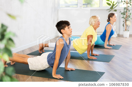Preteen boy practicing upward facing dog pose of yoga in fitness room Preteen boy practicing upward facing dog pose of yoga in fitness room 106987830