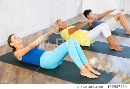 Mom, grandmother and teen grandson performing exercises to strengthen press, pump muscles of core 106987834